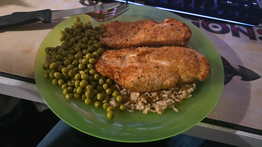 Breaded air fried chicken breast's with rice cooked in a rice cooker and peas cooked in the microwave.
