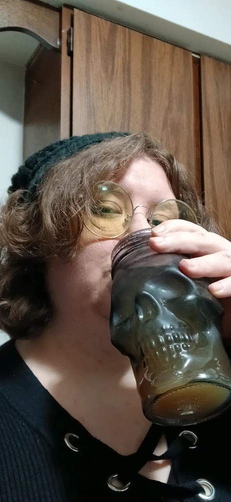 An NB sips apple cider from a skull shaped mason jar.